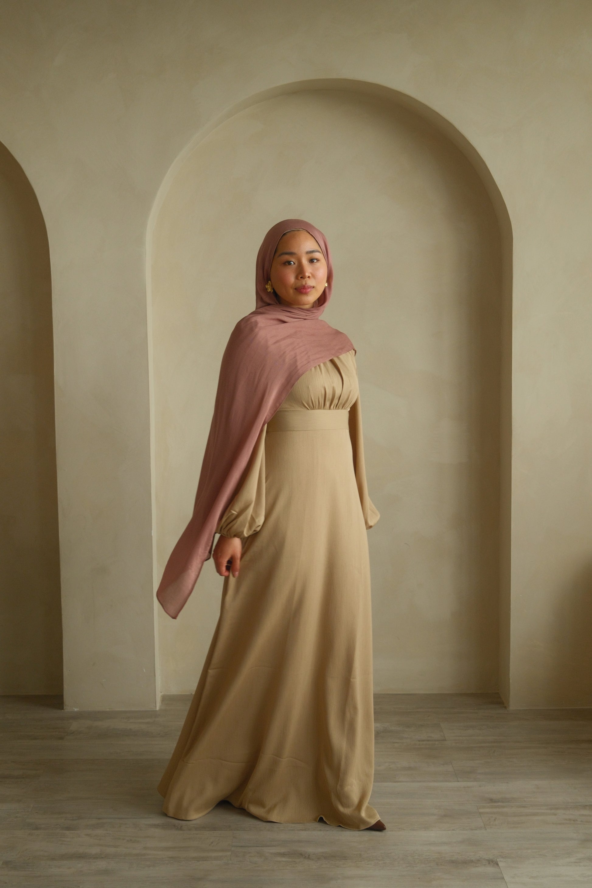 Hijabi women wearing premium modal hijab in the color dusty pink and long maxi dress in the color beige by the brand malika the collection