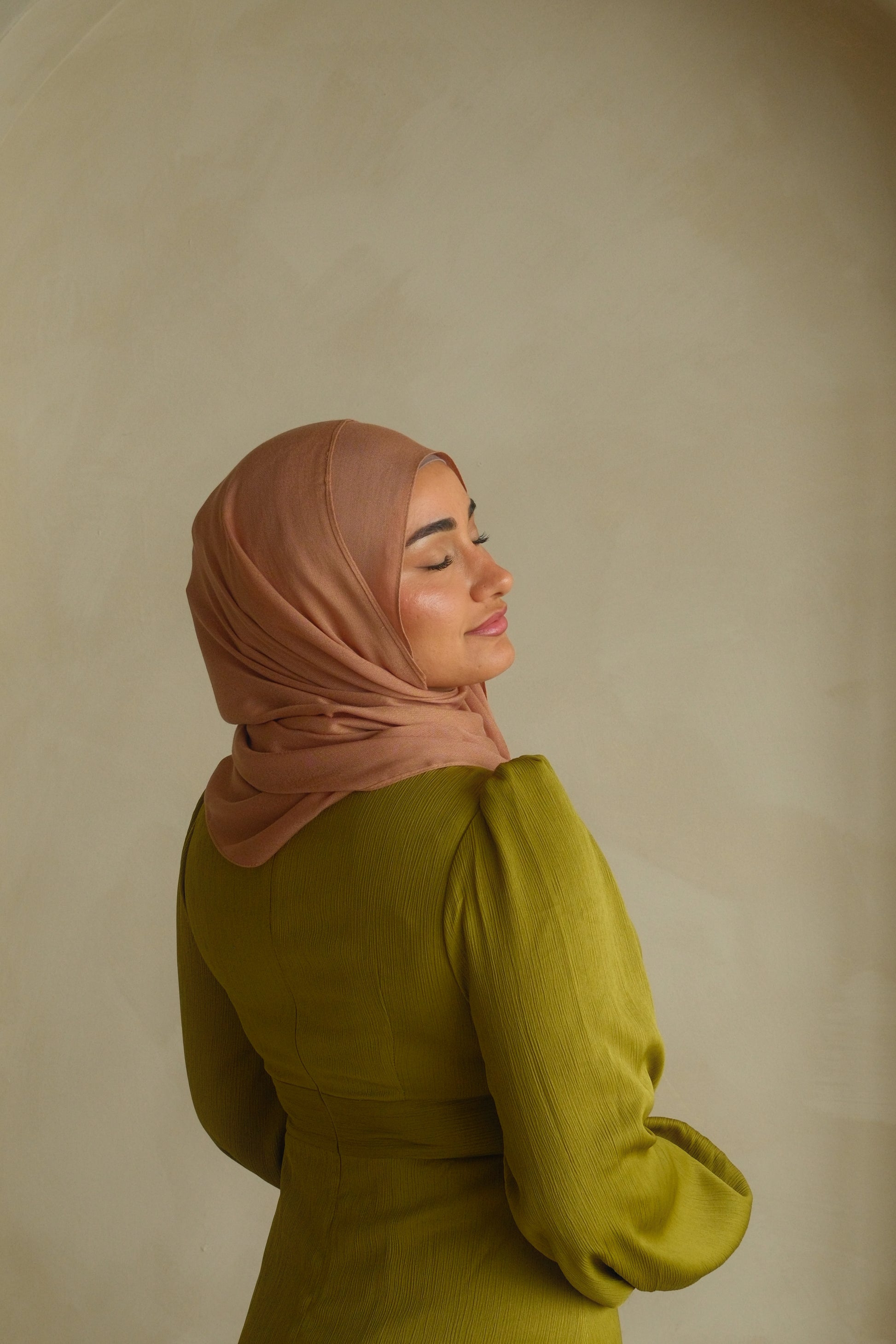 Hijabi women wearing a brown hijab in the color dunes and green modest dress by the brand malika the collection 