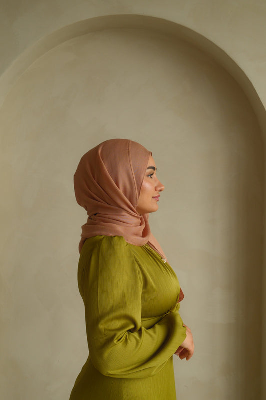 Hijabi women wearing a brown hijab in the color dunes and green modest dress by the brand malika the collection 