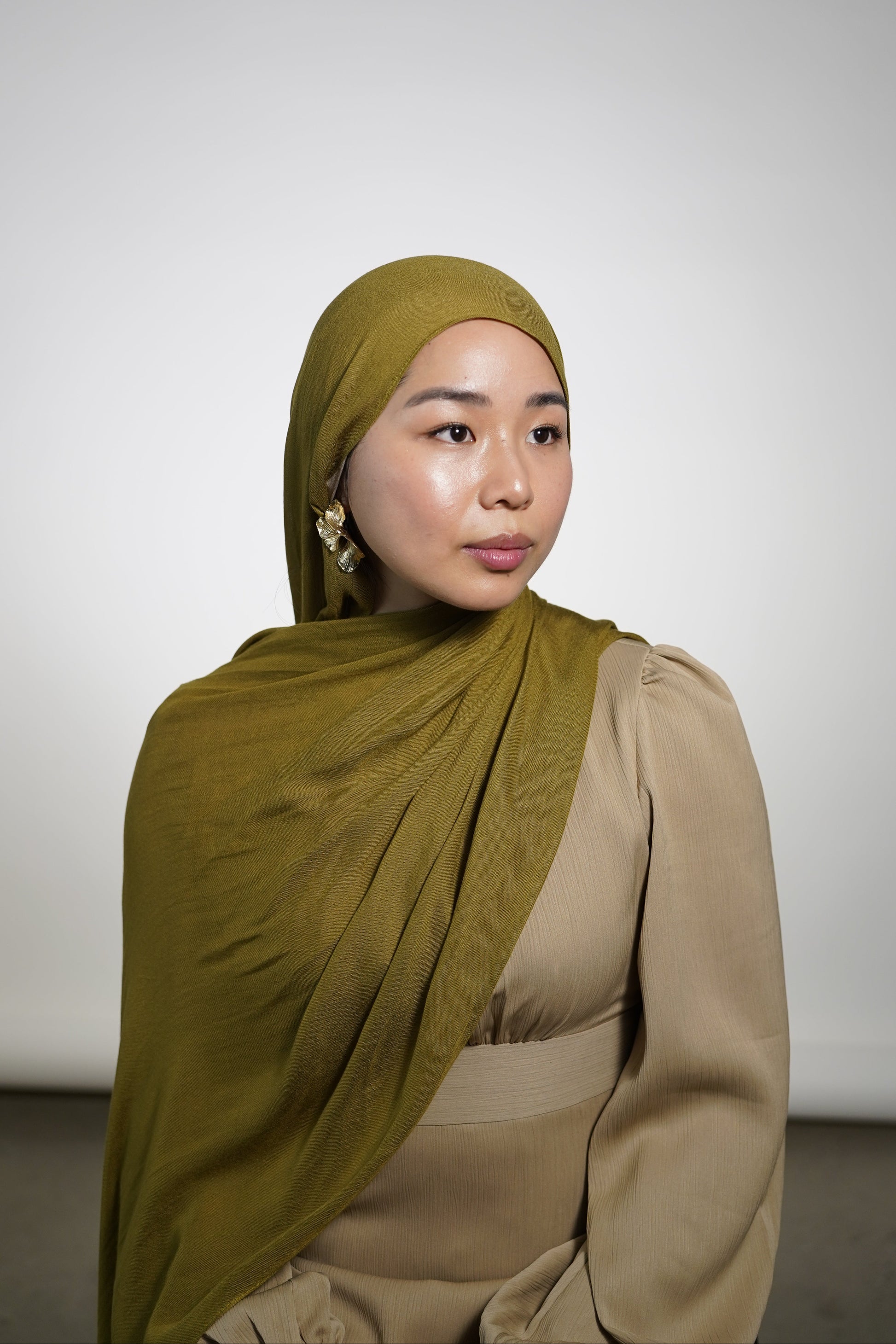Women wearing the amina dress in the color soft sand and premium modal hijab in the color moss by the brand malika the collection